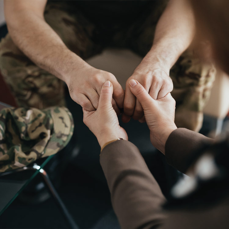 A woman's hands holding the hands of a male veteran